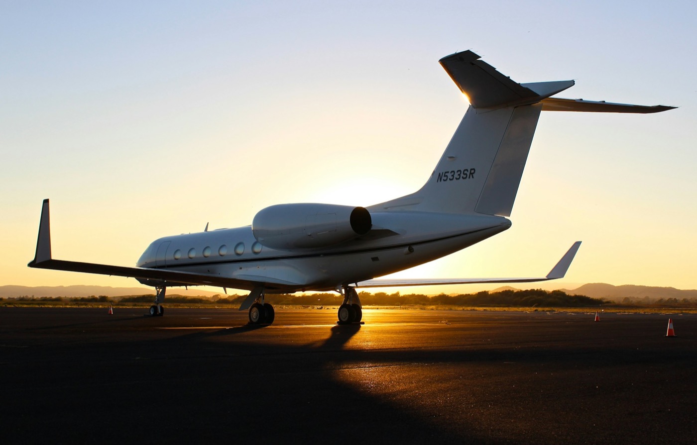 Private jet silhouetted at sunset