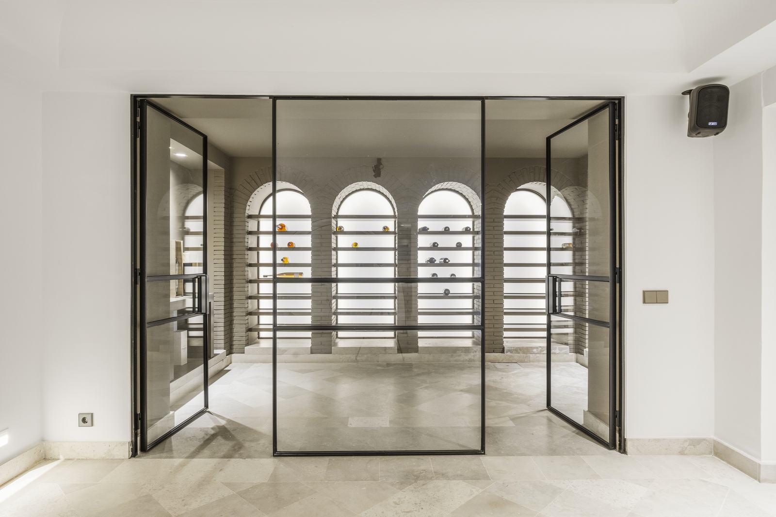 Glass double door standing open onto a lit vaulted cellar